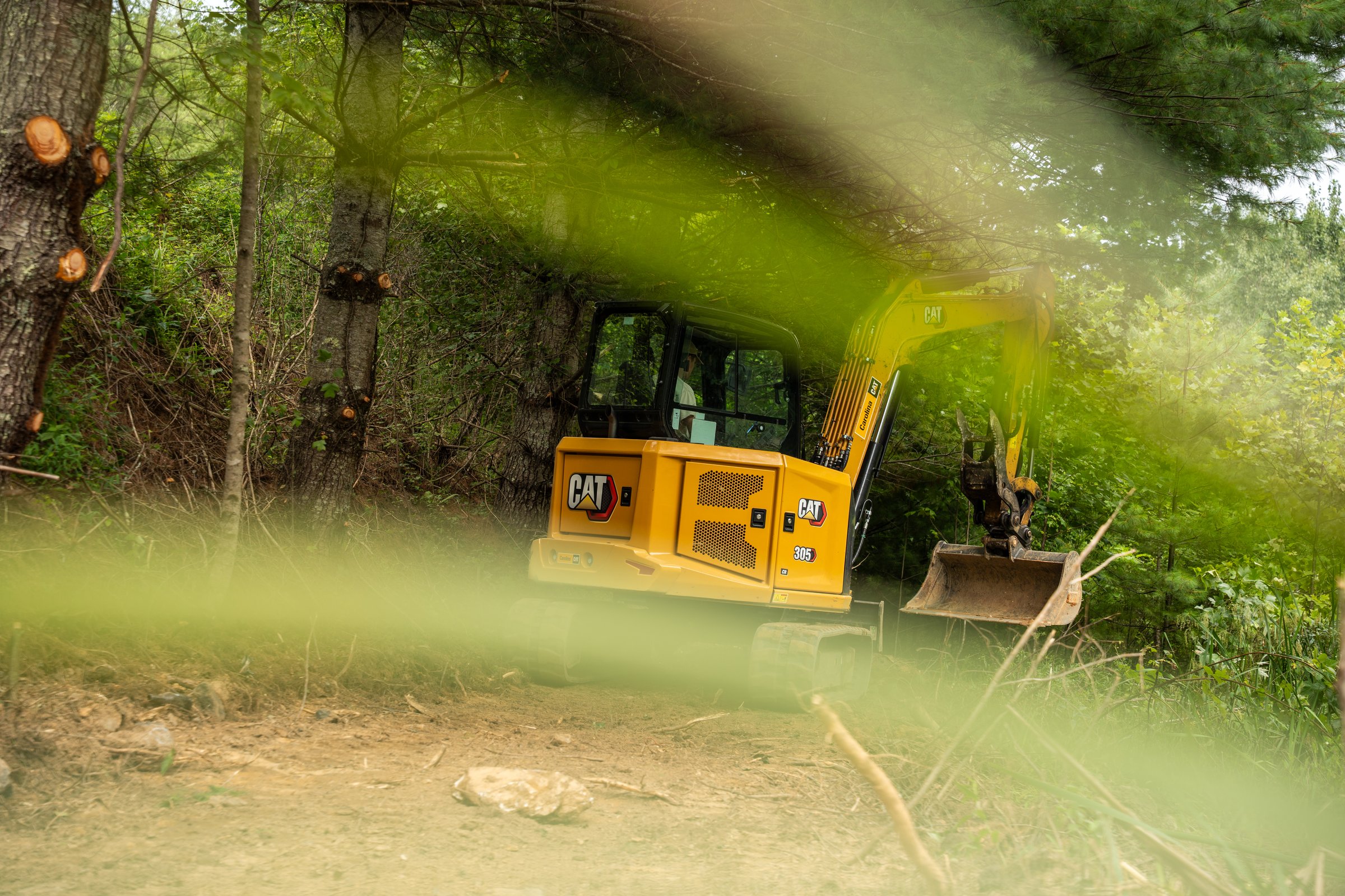 CAT 305 excavator working a wooded job site