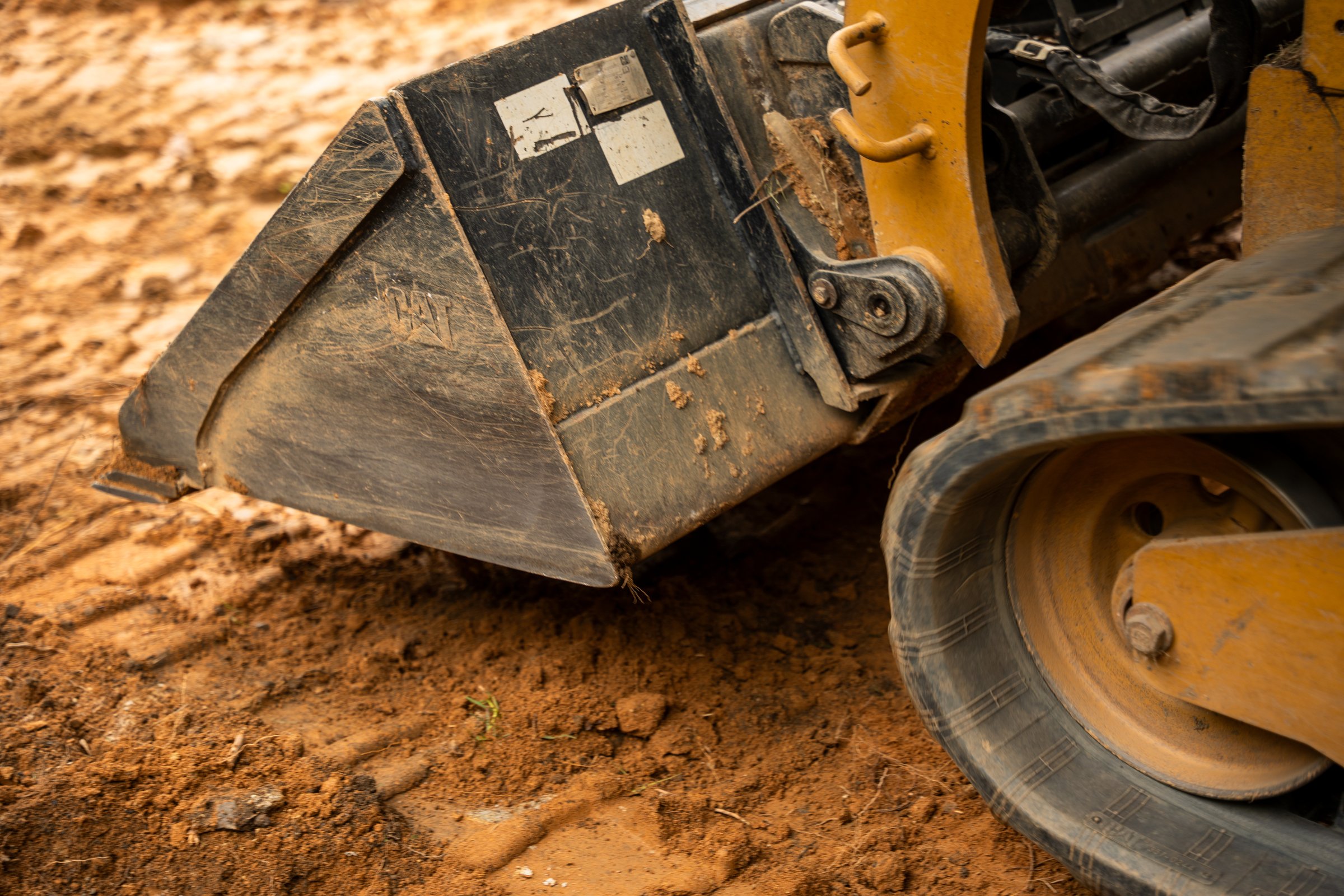 Close-up of a loader bucket in red clay